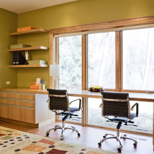 Design ideas for a contemporary home office in Minneapolis with green walls, medium hardwood floors and a built-in desk.