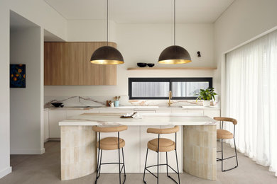 This is an example of a large contemporary l-shaped open plan kitchen in Sydney with with island, an undermount sink, flat-panel cabinets, white cabinets, beige splashback, grey floor and beige benchtop.