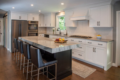 Eat-in kitchen - large country laminate floor and brown floor eat-in kitchen idea in Boston with an undermount sink, shaker cabinets, white cabinets, marble countertops, white backsplash, subway tile backsplash, an island and gray countertops