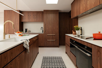 Kitchen - large 1960s limestone floor, beige floor and vaulted ceiling kitchen idea in Seattle with an undermount sink, flat-panel cabinets, medium tone wood cabinets, quartz countertops, white backsplash, quartz backsplash, black appliances, an island and white countertops