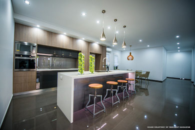 Kitchen in Darwin with a double-bowl sink, medium wood cabinets, granite benchtops, metallic splashback, glass tile splashback, stainless steel appliances and with island.