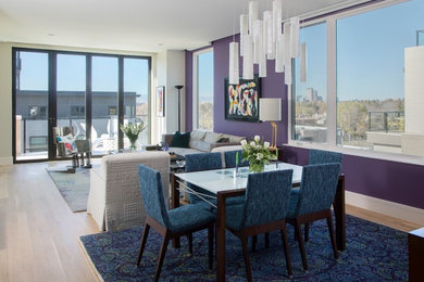 This is an example of a contemporary open plan dining in Denver with purple walls and light hardwood floors.