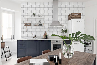 This is an example of an industrial open plan kitchen in Stockholm with white floor.