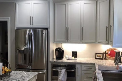 Eat-in kitchen - mid-sized transitional l-shaped dark wood floor and brown floor eat-in kitchen idea in Birmingham with an undermount sink, recessed-panel cabinets, white cabinets, white backsplash, stainless steel appliances and an island