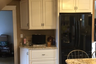 Eat-in kitchen - mid-sized transitional galley porcelain tile eat-in kitchen idea in Boston with an undermount sink, raised-panel cabinets, white cabinets, granite countertops, black appliances and an island