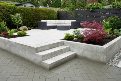 Photo of a mid-sized modern full sun backyard concrete paver and wood fence landscaping in Vancouver.