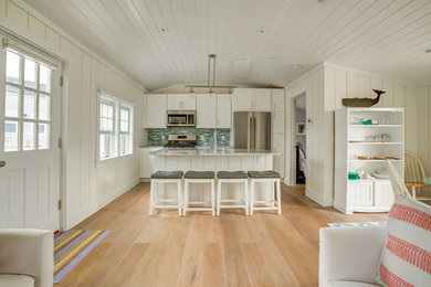 Open concept kitchen - mid-sized coastal light wood floor and brown floor open concept kitchen idea in Other with shaker cabinets, white cabinets, granite countertops, green backsplash, matchstick tile backsplash, stainless steel appliances and an island