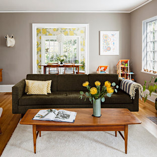 Idéer för mellanstora funkis separata vardagsrum, med grå väggar, mellanmörkt trägolv, en spiselkrans i tegelsten och en standard öppen spis