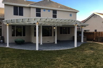 Inspiration for a mid-sized transitional backyard stamped concrete patio kitchen remodel in Other with a pergola