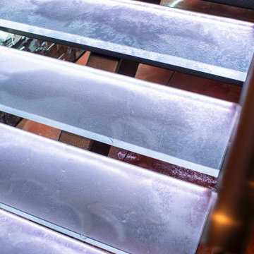 Glass private bar and glass stair treads inside a man cave in Michigan