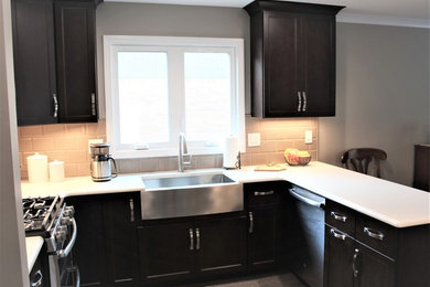 Inspiration for a mid-sized transitional u-shaped laminate floor and multicolored floor eat-in kitchen remodel in Detroit with a farmhouse sink, recessed-panel cabinets, dark wood cabinets, quartz countertops, beige backsplash, ceramic backsplash, stainless steel appliances, a peninsula and white countertops
