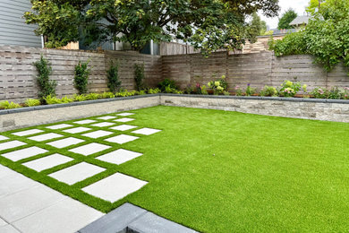 Inspiration for a mid-sized modern partial sun backyard concrete paver and wood fence retaining wall landscape in Seattle for summer.