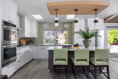 Inspiration for a huge transitional l-shaped medium tone wood floor and beige floor open concept kitchen remodel in Other with an undermount sink, shaker cabinets, white cabinets, quartz countertops, beige backsplash, glass tile backsplash, stainless steel appliances, an island and multicolored countertops