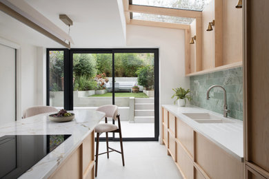 Inspiration for a medium sized contemporary single-wall kitchen/diner in London with raised-panel cabinets, light wood cabinets, quartz worktops, green splashback, marble splashback, stainless steel appliances, porcelain flooring, an island, grey floors and white worktops.