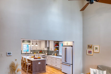 ワシントンD.C.にある高級な広いトランジショナルスタイルのおしゃれなアイランドキッチン (フラットパネル扉のキャビネット、白いキャビネット、クオーツストーンカウンター、緑のキッチンパネル、セラミックタイルのキッチンパネル、白いキッチンカウンター) の写真
