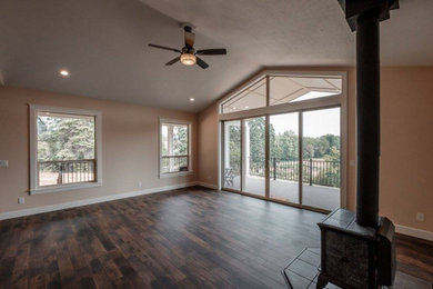 Example of an open concept brown floor living room design in Portland with beige walls and a wood stove