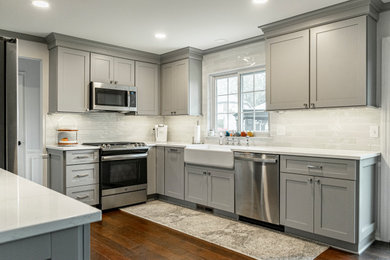 Eat-in kitchen - large transitional u-shaped medium tone wood floor eat-in kitchen idea in Detroit with a farmhouse sink, recessed-panel cabinets, gray cabinets, quartz countertops, white backsplash, ceramic backsplash, stainless steel appliances, no island and white countertops