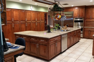 Large elegant u-shaped ceramic tile enclosed kitchen photo in Miami with an undermount sink, stainless steel appliances, raised-panel cabinets, medium tone wood cabinets, granite countertops, beige backsplash, stone slab backsplash and an island