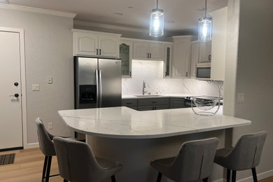 Example of a mid-sized transitional u-shaped laminate floor and beige floor eat-in kitchen design in Other with an undermount sink, raised-panel cabinets, gray cabinets, quartz countertops, white backsplash, quartz backsplash, stainless steel appliances, a peninsula and white countertops