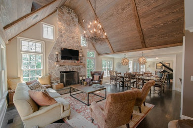 Inspiration for a large coastal open concept dark wood floor living room remodel in New York with beige walls, a standard fireplace, a stone fireplace and a wall-mounted tv