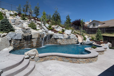 Design ideas for a large tropical backyard custom-shaped pool in Sacramento with a water slide and stamped concrete.