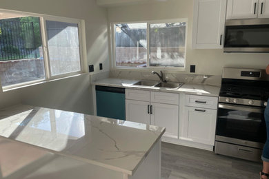 Eat-in kitchen - mid-sized vinyl floor and beige floor eat-in kitchen idea in Los Angeles with a double-bowl sink, shaker cabinets, white cabinets, quartzite countertops, white backsplash, quartz backsplash, stainless steel appliances, an island and white countertops