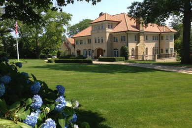 Inspiration for an expansive mediterranean three-storey beige house exterior in New York with stone veneer, a gable roof and a shingle roof.