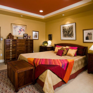 Esempio di una camera matrimoniale etnica con pareti gialle e moquette