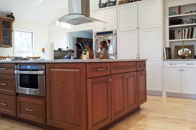 Large transitional u-shaped eat-in kitchen in New York with a double-bowl sink, shaker cabinets, white cabinets, granite benchtops, stainless steel appliances, bamboo floors and with island.