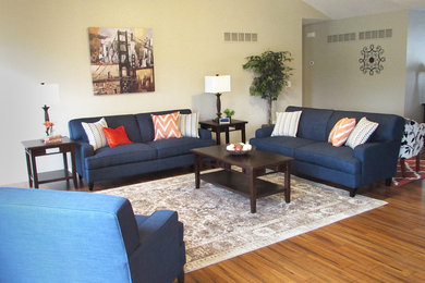 Living room - mid-sized transitional formal and open concept medium tone wood floor and brown floor living room idea in St Louis with beige walls, no tv, a standard fireplace and a brick fireplace