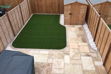 Design ideas for a small modern back patio in Sussex with natural stone paving.