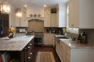 Example of a mid-sized transitional u-shaped dark wood floor and brown floor enclosed kitchen design in Chicago with a farmhouse sink, shaker cabinets, white cabinets, granite countertops, gray backsplash, porcelain backsplash, stainless steel appliances and an island