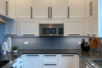 Inspiration for a mid-sized transitional u-shaped dark wood floor and brown floor eat-in kitchen remodel in Chicago with an undermount sink, recessed-panel cabinets, white cabinets, quartz countertops, blue backsplash, ceramic backsplash, stainless steel appliances, no island and gray countertops