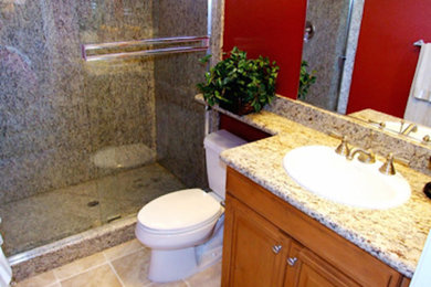 Example of a mid-sized 3/4 ceramic tile alcove shower design in DC Metro with an undermount sink, raised-panel cabinets, medium tone wood cabinets, granite countertops, a two-piece toilet and red walls