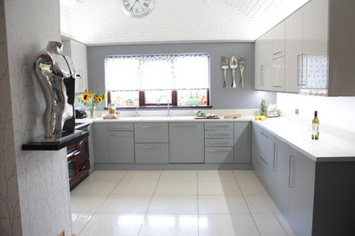 Inspiration for a mid-sized modern u-shaped open plan kitchen in Belfast with a single-bowl sink, flat-panel cabinets, grey cabinets, laminate benchtops, grey splashback, glass sheet splashback and porcelain floors.
