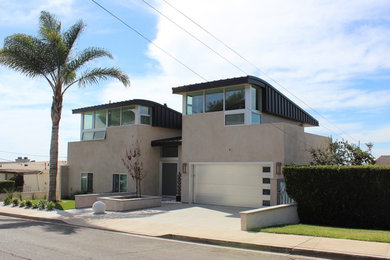 Example of a mid-sized trendy beige three-story stucco house exterior design in San Diego with a shed roof and a metal roof