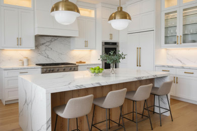 Eat-in kitchen - mid-sized transitional galley light wood floor and brown floor eat-in kitchen idea in Charlotte with a farmhouse sink, shaker cabinets, white cabinets, quartz countertops, white backsplash, quartz backsplash, stainless steel appliances, an island and white countertops