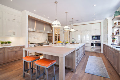 Example of a transitional medium tone wood floor kitchen design in Miami with an undermount sink, shaker cabinets, white cabinets, white backsplash, stainless steel appliances and an island