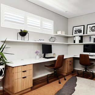Design ideas for a contemporary home office in Sydney with grey walls, medium hardwood floors, a built-in desk and brown floor.