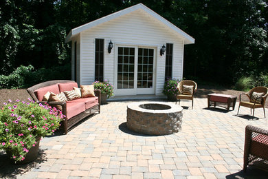 Mid-sized trendy backyard stone patio photo in New York with a fire pit