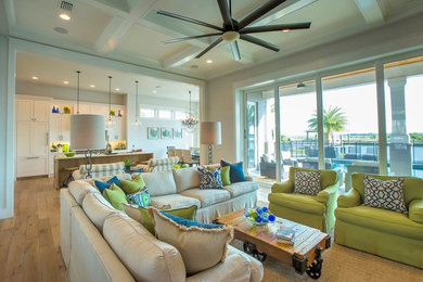 Photo of a large beach style open concept living room in Jacksonville with white walls, light hardwood floors, a standard fireplace, a wall-mounted tv and a brick fireplace surround.