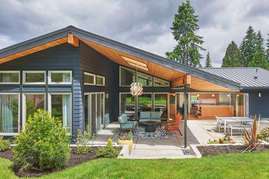 Mid-sized midcentury one-storey grey house exterior in Seattle with a gable roof and a metal roof.