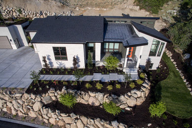 Large modern white one-story stone exterior home idea in Salt Lake City with a shed roof