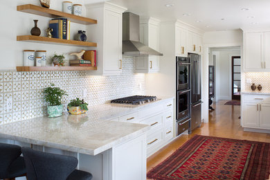 Inspiration for a transitional u-shaped kitchen in San Diego with shaker cabinets, white cabinets, white splashback, stainless steel appliances, medium hardwood floors and a peninsula.
