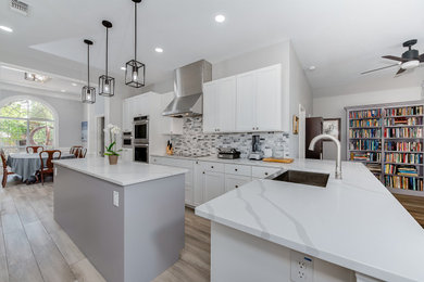 Example of a minimalist porcelain tile eat-in kitchen design in Austin with a farmhouse sink, quartz countertops, multicolored backsplash, marble backsplash, an island and white countertops