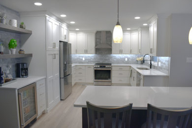 Inspiration for a mid-sized modern u-shaped light wood floor and brown floor eat-in kitchen remodel in Other with a drop-in sink, white cabinets, quartz countertops, gray backsplash, glass tile backsplash, stainless steel appliances, an island and white countertops