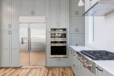 Example of a large transitional u-shaped medium tone wood floor eat-in kitchen design in Austin with shaker cabinets, green cabinets, quartzite countertops, white backsplash, stainless steel appliances, no island, white countertops and ceramic backsplash