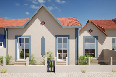 Aménagement d'une façade de maison mitoyenne blanche bord de mer en stuc de taille moyenne et de plain-pied avec un toit à deux pans, un toit en tuile et un toit rouge.