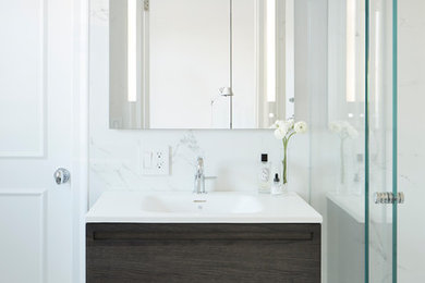 Photo of a mid-sized modern master bathroom in New York with furniture-like cabinets, grey cabinets, an open shower, a one-piece toilet, black and white tile, porcelain tile, white walls, porcelain floors and a wall-mount sink.