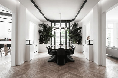 Expansive contemporary open plan dining in Paris with white walls and light hardwood floors.